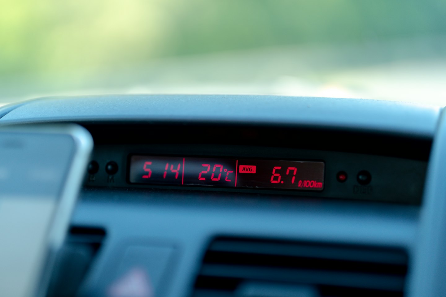 Car dashboard digital display showing time and fuel consumption.