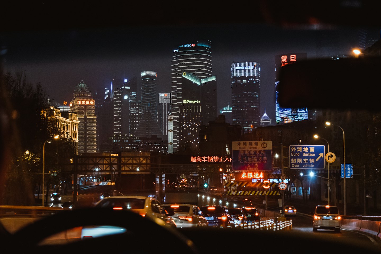 Car driving through a city at night with neon lights.