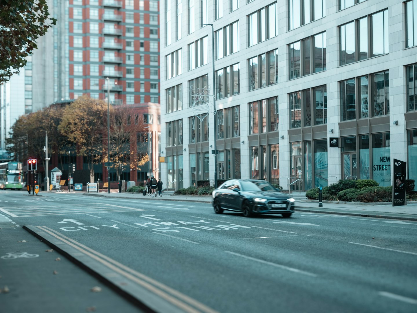 A car drives down an urban street lined with buildings.