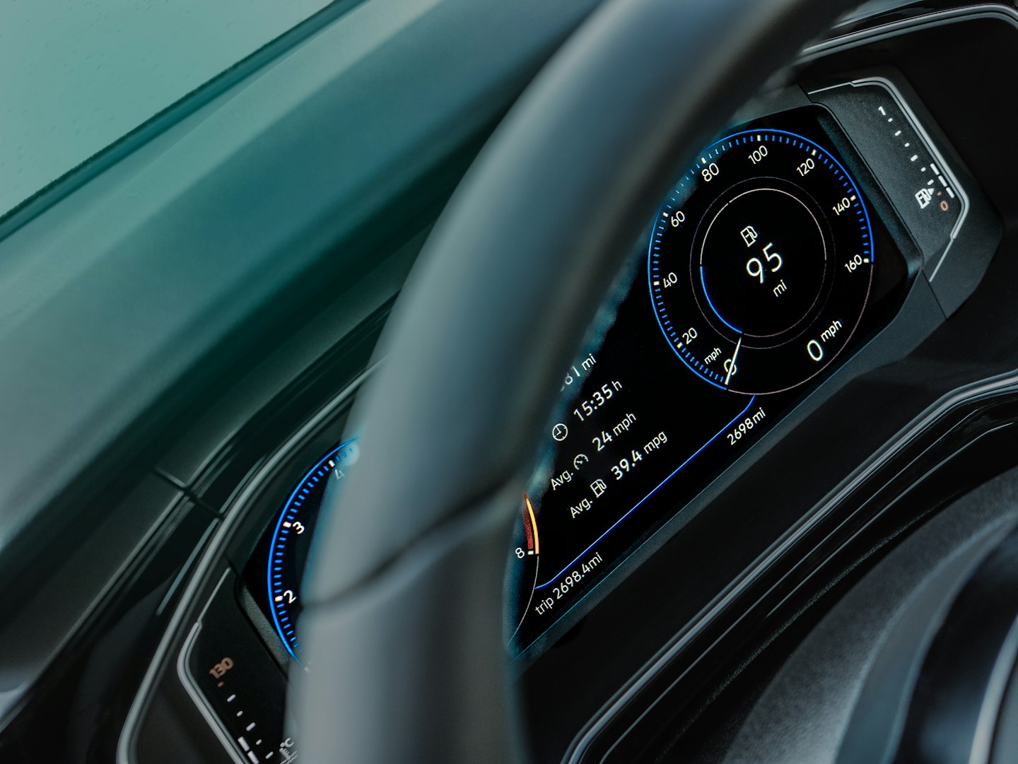 Modern car dashboard displays driving metrics behind a steering wheel.